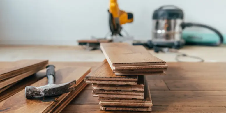 Stack of new hardwood flooring planks with a hammer, ready for installation