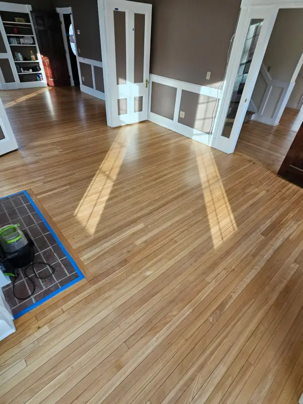 After: the same living room floor restored to an even natural finish