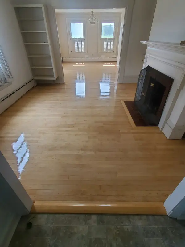 After: the same fireplace room floor refinished with a glossy natural finish