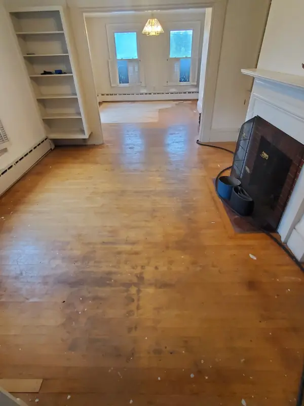 Before: scuffed old hardwood floor in a room with a fireplace