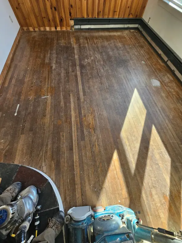 Before: worn dark oak sunroom floor being sanded